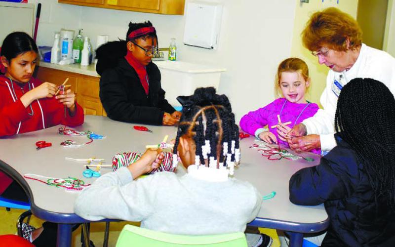 PutnamARTS Chairperson Janet Kelho_er, who is in charge of the after-school program, helps kids to make a Christmas ornament named “God’s eyes.”