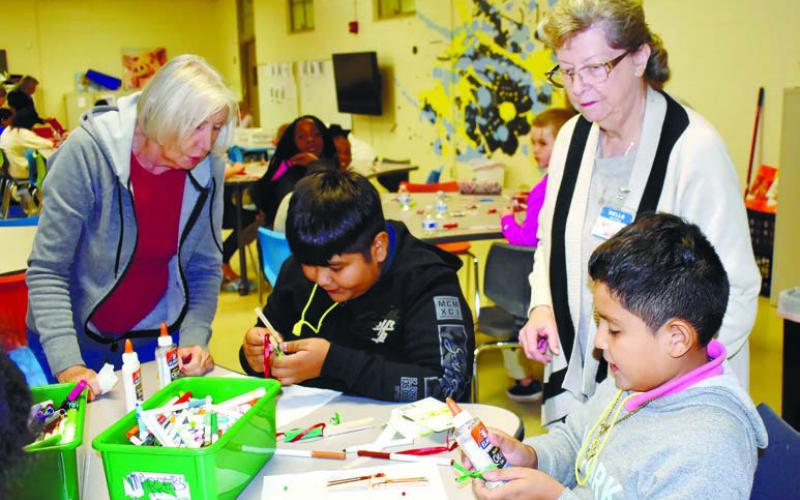 Instructors Annette Burrell (left) and Sandra Gann help brothers Yamil and Sayd Vargas make reindeer ornaments out of clothes pins.