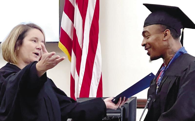 Superior Court Judge Alison Burleson welcomes Bashun Carter to the podium as he accepts his PAC graduation certificate.