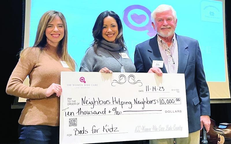 100+ Women Who Care representatives present NHN President Bob Massey (right) with a $10,000 check to support the organization. CONTRIBUTED