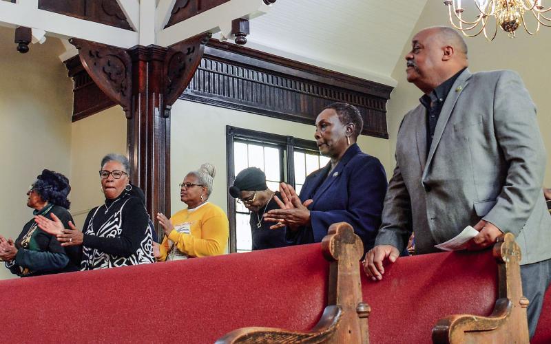 Community members rise during song and prayer. IAN TOCHER/Staff