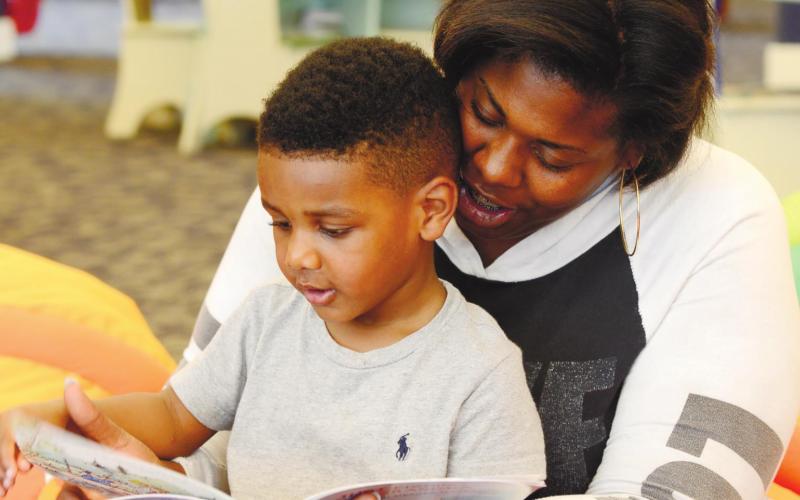 A mother and her son read a book together. CONTRIBUTED