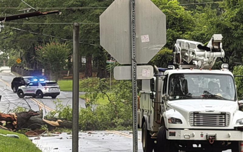 A crew from Georgia Power Company is on hand to evaluate damage after a large tree hit and broke a utility pole at the corner of Church and Grove streets in Eatonton Saturday. VICTORIA ANADENKO/Staff