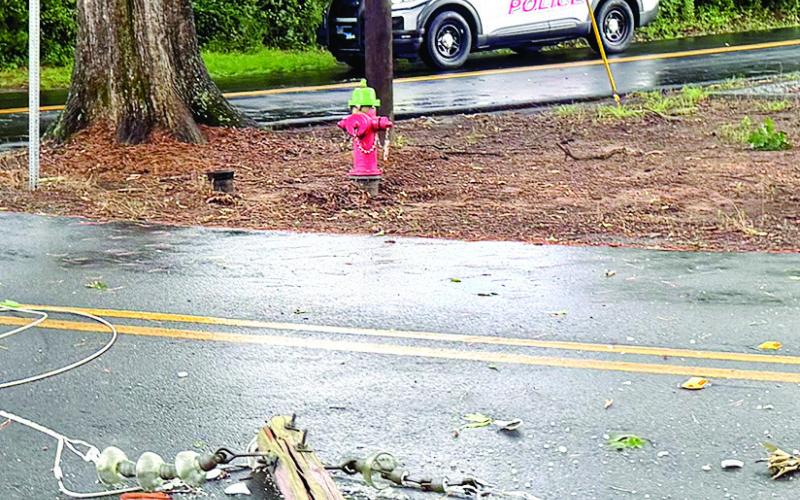 The top of a broken utility pole rests in the road after being broken and knocked down by a large tree. Power was restored around 2 a.m. Sunday for residents along Church and Grove streets in Eatonton. VICTORIA ANADENKO/Staff