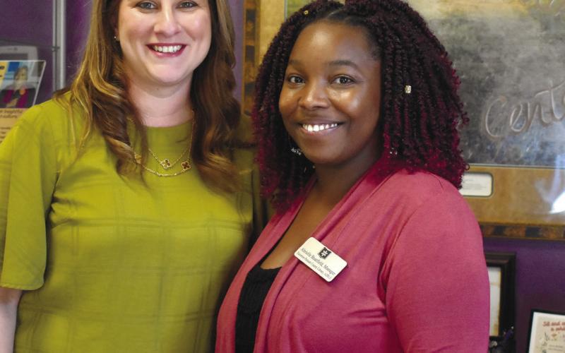 Georgia Writers Museum Executive Director Melissa Swindell and Eatonton-Putnam County Library Manager Abrielle Boatfield stand in front of the writing desk inside the mini-museum. BAILEY MCCULLY/Staff