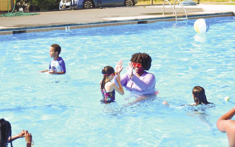 Camp instructor Rakeena Griffin high-fives third-grader Skylar Bridges, who just successfully swam up to her covering some distance in water.