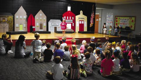 Classmates watch K-4 student Macey Duvall showing off her shirt that states, “100 Days Sprinkled with Fun.”