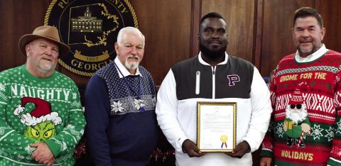 On behalf of his fellow coaches and a roster 39 players, Alexander Banks, head coach of the 2025 Putnam County Middle School War Eagles football team, accepted a framed proclamation last Tuesday night recognizing the team’s 2025 state championship from (l-r) Commissioner Jeff Wooten, Chairman Bill Sharp, and Commissioner Tom McElhenney. IAN TOCHER/Staff