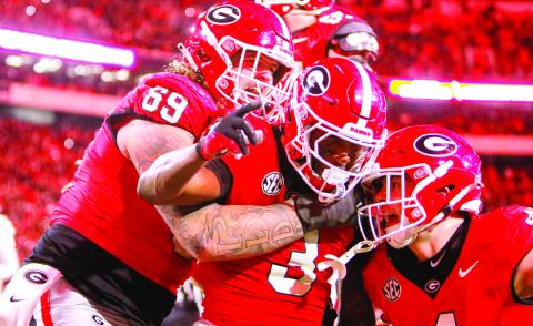 Nate Frazier (3) celebrates with teammates after scoring a game-winning two-point conversion for Georgia during the eighth overtime against rival Georgia Tech. LANCE McCURLEY/Staff