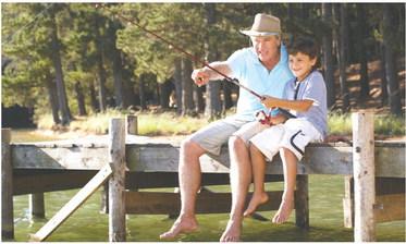 Dad showing his son how to reel in a fish. STOCK PHOTO