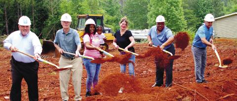 Throwing the first shovelfuls of dirt were (l-r): Bill Gower of Farmers and Merchants Bank, Habitat for Humanity’s Bucky Kahl, soon-to-be homeowner Camille Hyman with baby Carmoni, Habitat’s Jennifer Ishee, Eatonton Mayor John Reed and electrician Clay Lloyd. Hyman’s parents’ home is shown on the right. IAN TOCHER/Staff
