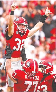 Georgia offensive lineman Tate Ratledge (77) holds up Cash Jones (32) after he scored a touchdown in the fourth quarter of the Bulldogs win over South Carolina last week. TONY WALSH/UGA Athletics