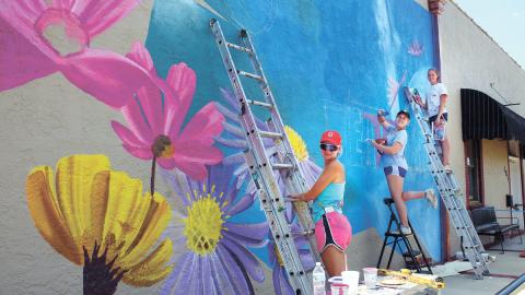 Painters work on a new mural in downtown Eatonton during the Dairy Festival, bringing color to the side of the building that houses Nails by Aaron at the corner of North Jefferson Avenue and Marion Street. IAN TOCHER/Staff