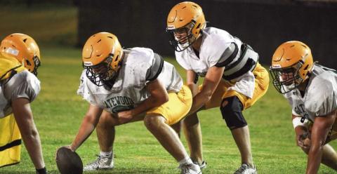 Gatewood sophomore quarterback Blake Brannen takes a snap from junior center Drew Burke during pre-season practice at Gatewood’s Sammons Field in Eatonton. IAN TOCHER/Staff
