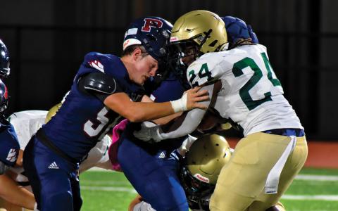Despite losing his helmet, Gavin Aultman continues to help running back Kumari Thomas push forward for extra yards last Friday night against Aquinas. BRANDON PARK/Staff