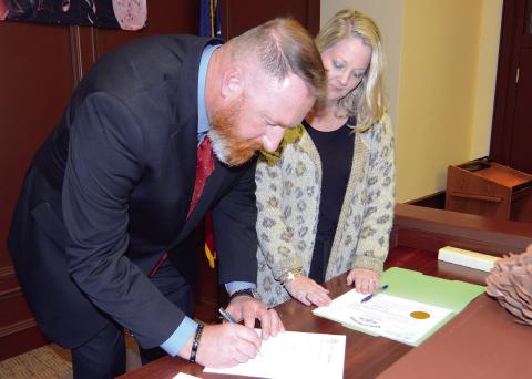 With Probate Court Judge Brandi T. Huskins by his side, Terrell Abernathy signs in for the first time as Putnam County’s newly installed Tax Commissioner. IAN TOCHER/Staff
