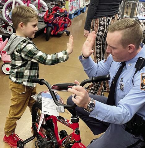Oliver Philippe, 6, spontaneously gives GSP Trooper Derek Snead a high five after he picked out a new bicycle. LYNN HOBBS/Staff
