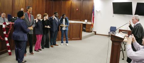 With Mayor John Reid seated behind them (far left), starting second from left, Councilmembers James Gorley, Teresa Doster, Mylle Mangum, and new addition Fredrick Lowe face Putnam County State Court Judge Michael Gailey (far right), who administered the Jan. 6 swearing-in ceremony at the county administration building. IAN TOCHER/Staff