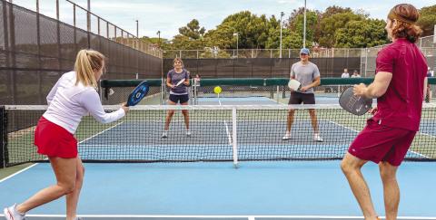 Dedicated pickleball courts appear like mini tennis courts, while the rackets look like oversized ping-pong paddles. The ball itself is plastic with holes throughout, similar to what’s commonly known as a whiffle ball. Mixed doubles (shown) is a very popular team option for the socially oriented sport. CONTRIBUTED