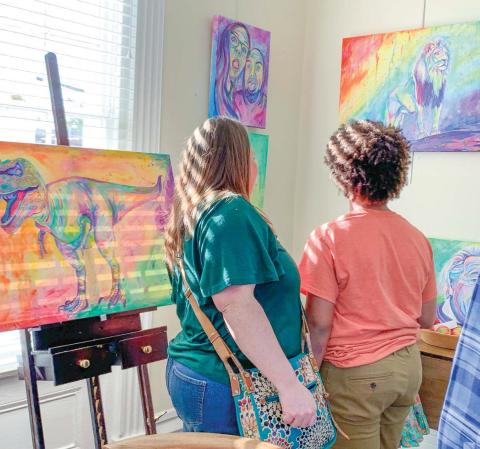 Two attendees view “Chromatic King” (right) that depicts a lion looking out beyond where it stands.
