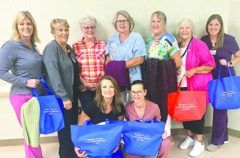 Felicia McDonel, Carole Dunagan, Donna Birt, Debbie Skinner, Lou Rodeheaver, PGH Auxiliary President Joan Millines (with red bag) and Suzanne Culp, with PHG Case Manager Lisa English and Donna Price in front. CONTRIBUTED