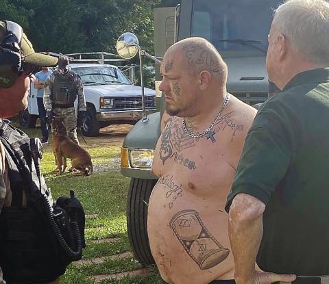 Andy Kirk Davis, center, being held by Putnam County Sheriff’s Lt. Harry Luke, right, is questioned by Butts County Sheriff’s detectives outside Davis’ Putnam County home in 2020. CONTRIBUTED/PCSO