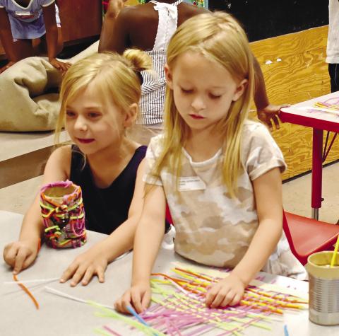 Josie Holder and Cadence Reid weave pipe cleaners together to decorate their pencil holders. LENA HENSLEY/Staff