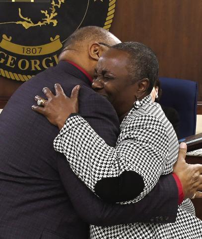 Eatonton Mayor John Reid hugs his wife, Janie, at the close of her outgoing city council meeting on Monday night. IAN TOCHER/Staff
