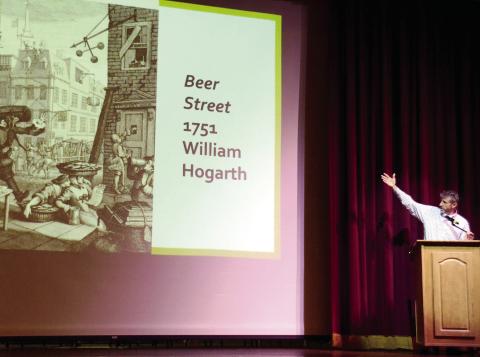 GCSU’s Dr. Eric Tenbus gestures toward the “Beer Street” political cartoon of artist William Hogarth during his talk at The Plaza Arts Center on Sunday afternoon. IAN TOCHER/Staff