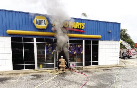 A City of Eatonton firefighter approaches the front door of the NAPA Auto Parts store on South Oak Street early Tuesday morning as Putnam County firefighters prepare their ladder truck in the side parking lot. COURTESY OF EATONTON FIRE DEPARTMENT