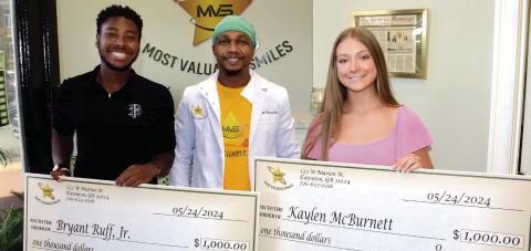 Recent Putnam County High School graduates Bryant Ruff Jr. (far left) and Kaylen McBurnett (far right) $1,000 scholarships from Most Valuable Smiles Dentistry in downtown Eatonton. (IAN TOCHER/Staff)