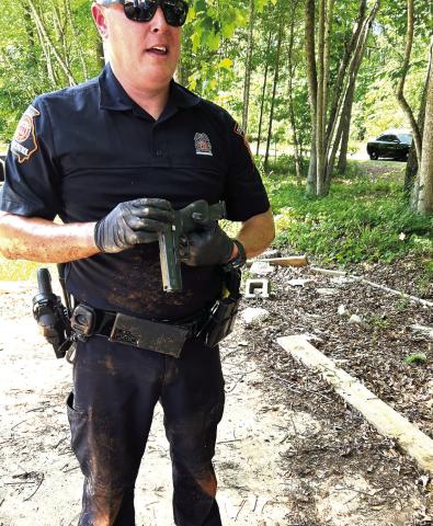 GSP Trooper Alan Rhodes holds the gun recovered from underneath the trailer after PCSO Col. Russell Blenk, EPD Chief Howell Cardwell, PCSO Sgt. Justin Brock and Cpl. Chris Donovan had gone under there and gotten the offenders out. CONTRIBUTED/EPD