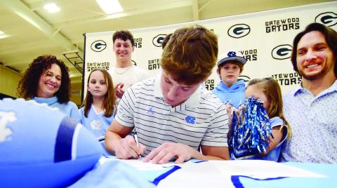 Surrounded by his family, including mother Christine and his father, Dan, Evan Bennett put pen to paper on his commitment contract with the University of North Carolina last Wednesday in Eatonton. IAN TOCHER/Staff