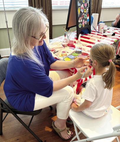 Five-year-old Evelyn Mallinson gets her face painted with a pink flower. (EMMA CLAUSE/Staff)