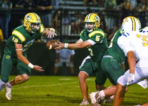 Filling in for injured quarterback Blake Brannen, sophomore Brady Haley (5) has been performing well, contributing a rushing touchdown against the Cavs, and shown here completing a handoff to junior running back Sean Bennett. IAN TOCHER/Staff