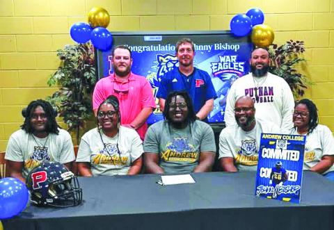 Surrounded by his family and with his coaches standing behind him, Putnam County’s Johnny Bishop (center) recently signed a commitment to attend and play football for Andrew College this fall. CONTRIBUTED