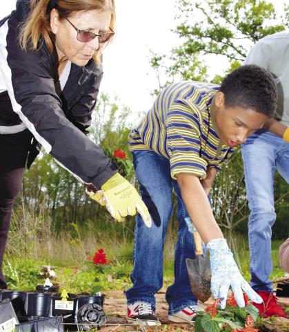 Volunteer Jonna Rubins Marchuk helps an APPLE student plant flowers at the Butterflies and Blooms habitat. IAN TOCHER/Staff