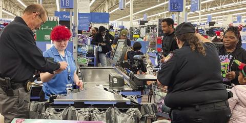 Eatonton Police Chief Howell Cardwell, right, pays the Walmart cashier as Investigator Hargrove Jones and Officer Rebecca Meeks load the purchases in carts during Shop with a Cop. LYNN HOBBS/Staff