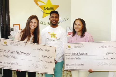 Dr. Willie Oliver of Most Valuable Smiles, presented Putnam County High School graduates Jenna McDerment (left) and Jaida Jackson with $500 scholarship checks last Friday. IAN TOCHER/Staff
