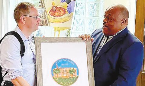 Mayor John Reid (right), presents a framed print of Eatonton City Hall to Mark Libell, chief of staff for Sen. Raphael Warnock. CONTRIBUTED