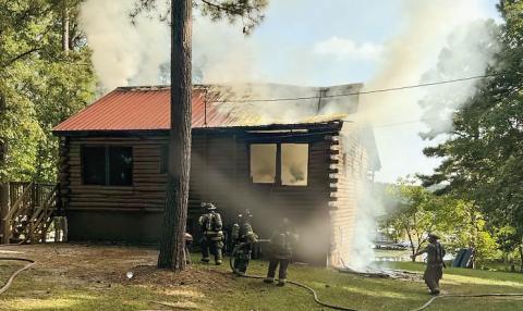 Putnam County Fire Dept. firefighters watch for flare ups amidst the smoke after putting out the flames of the fire in a log cabin on Rockville Springs Drive Monday. CONTRIBUTED