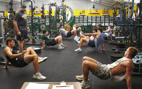 A group of veteran Gatewood football players goes through a drill in the weight room Tuesday morning, under the watchful eye of strength and conditioning coaches Scott Dennard and Conor Richards (far right). IAN TOCHER/Staff