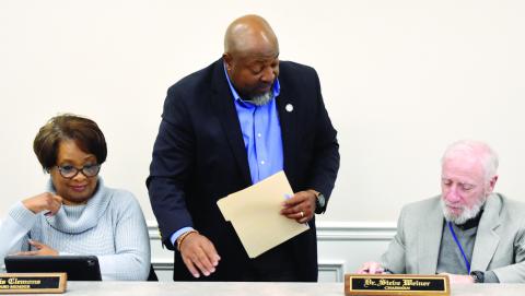 Austin (center) leans over Board Chair Dr. Steve Weiner’s shoulder as board members sign the approved contract. BAILEY McCULLY/Staff