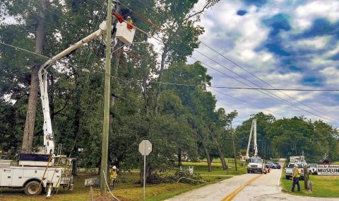 Crews work on downed limbs and power lines at the intersection of North Maple Avenue and Madison Road at the north end of Eatonton. IAN TOCHER/Staff