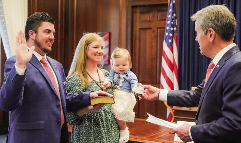 Putnam County Clerk of Courts Trevor Addison (left), with his wife Pelar (pronounced “Pil-arr”) holding a family Bible, was sworn in Feb. 25 by Georgia Governor Brian Kemp while the governor was holding the hand of Addison’s young daughter, Cora Rose. CONTRIBUTED