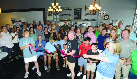 Shop co-owner Diana Homeier (left) and Paula Benjamin of the adjoining Georgia Writers Museum each held an end of the ceremonial red ribbon as Michael Homeier made the grand-opening cut last Friday to officially open Sylvia’s: A Supernatural Coffee Bar. IAN TOCHER/Staff