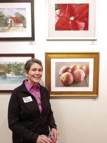 With two of her pastels, Linda Dudley is all smiles at the exhibit Wednesday evening. LEIGH LOFGREN/Staff