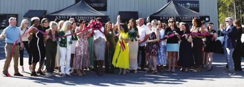 Adriana Velez (center with scissors) was joined by a large throng of business colleagues and well wishers last Thursday as she officially cut the ribbon to her new Ansley R.E.Christie’s Int’l. business center in a joint ceremony co-hosted by Eatonton-Putnam Chamber of Commerce President Robbie King and Greene County Chamber of Commerce President Mika Mills (both, far right). IAN TOCHER/Staff