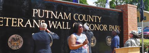Loretta Hampton sings the Star Spangled Banner while those attending the Memorial Day ceremony at Veterans Wall of Honor Park salute the American flag. T. MICHAEL STONE/ S t a ff