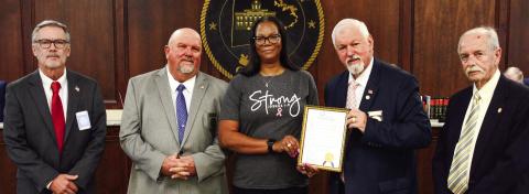 Before the start of the Oct. 4 Putnam County Commission meeting, Commission Chairman Bill Sharp (holding frame) invited County Human Resources Director Cynthia Miller to join him and (l-r) Commissioners Daniel Brown, Jeff Wooten, and Stephen Hersey in a proclamation recognizing the month of October as Breast Cancer Awareness Month. IAN TOCHER/Staff